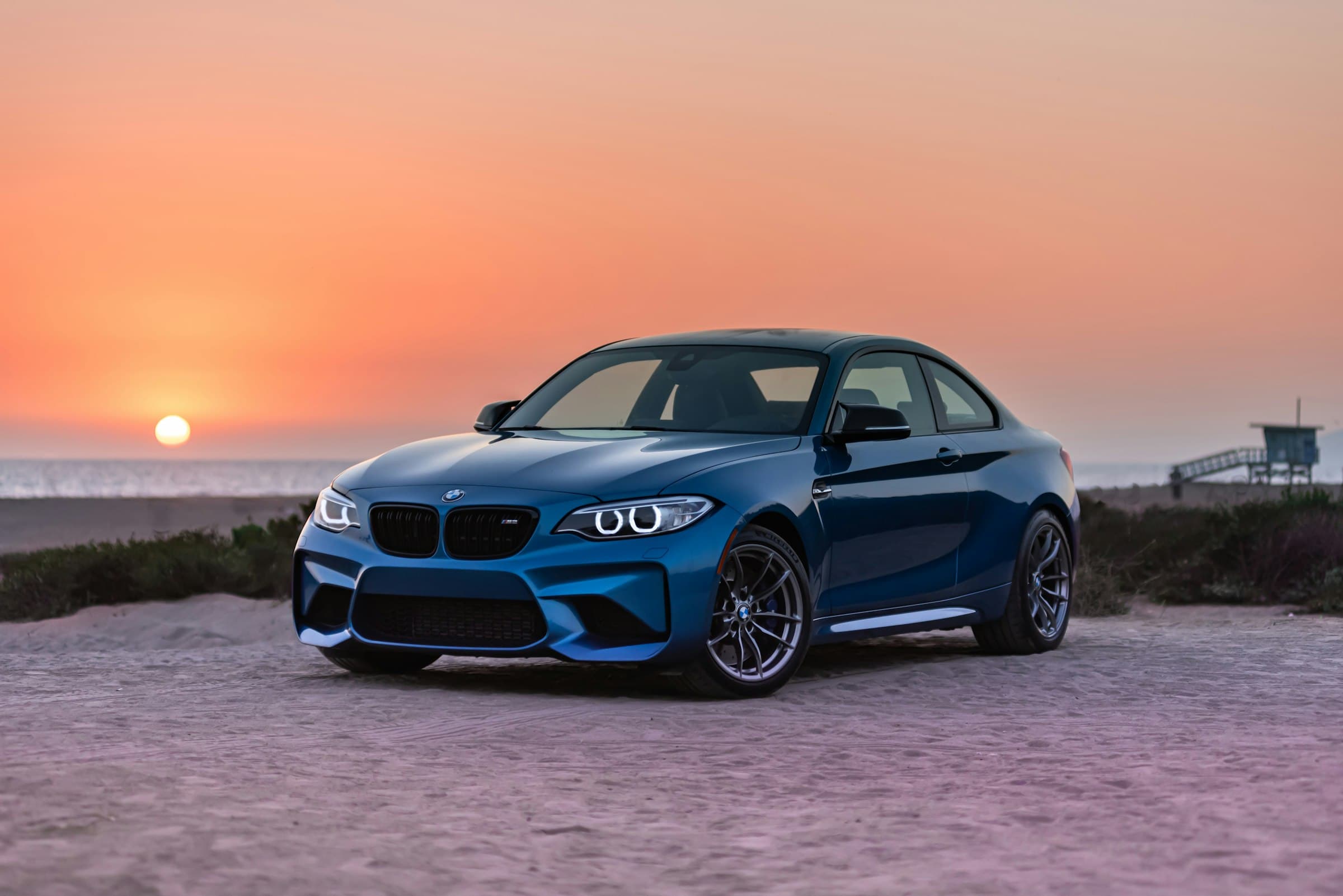 Detailed blue coupe facing the camera at sunset, headlights clear and paint gleaming